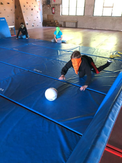 jeune avec un bandeau sur les yeus et jouant au ballon