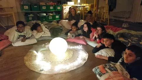 jeunes allongés au sol autour d'une lampe ronde